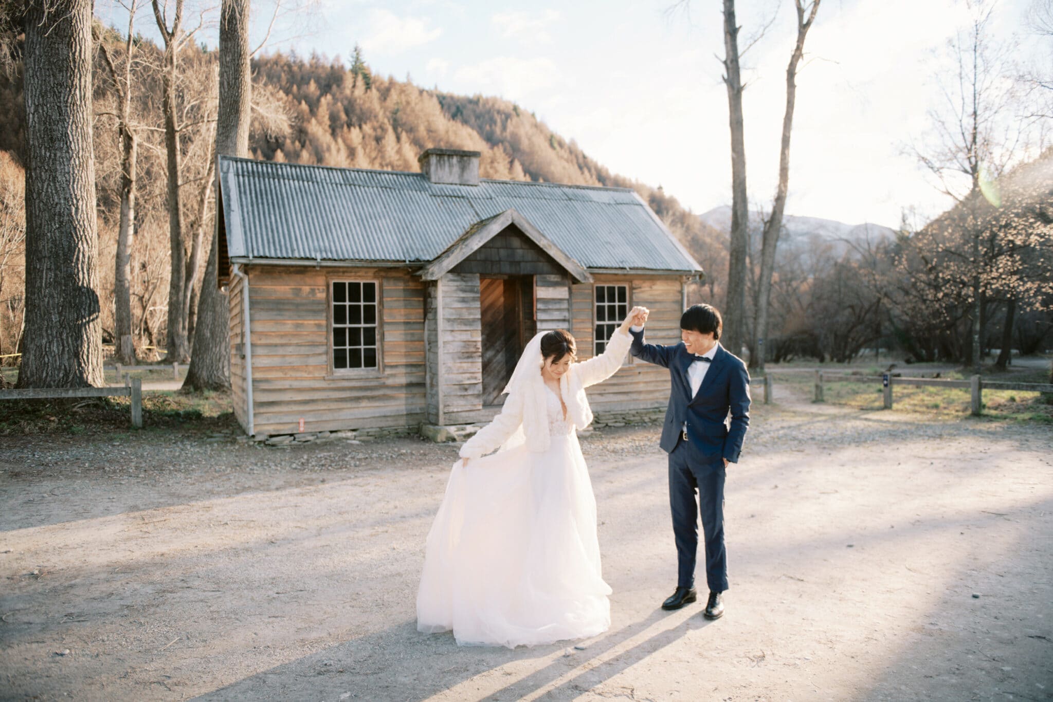 Queenstown Tekapo New Zealand Heli Wedding Elopement Pre-Wedding Shoot Photographer クイーンズタウン　テカポ　ニュージーランド　エロープメント 前撮り　フォトウェディング　結婚式 | A newlywed couple sharing a dance in front of a rustic cabin in a picturesque countryside setting during their Tekapo pre-wedding shoot.